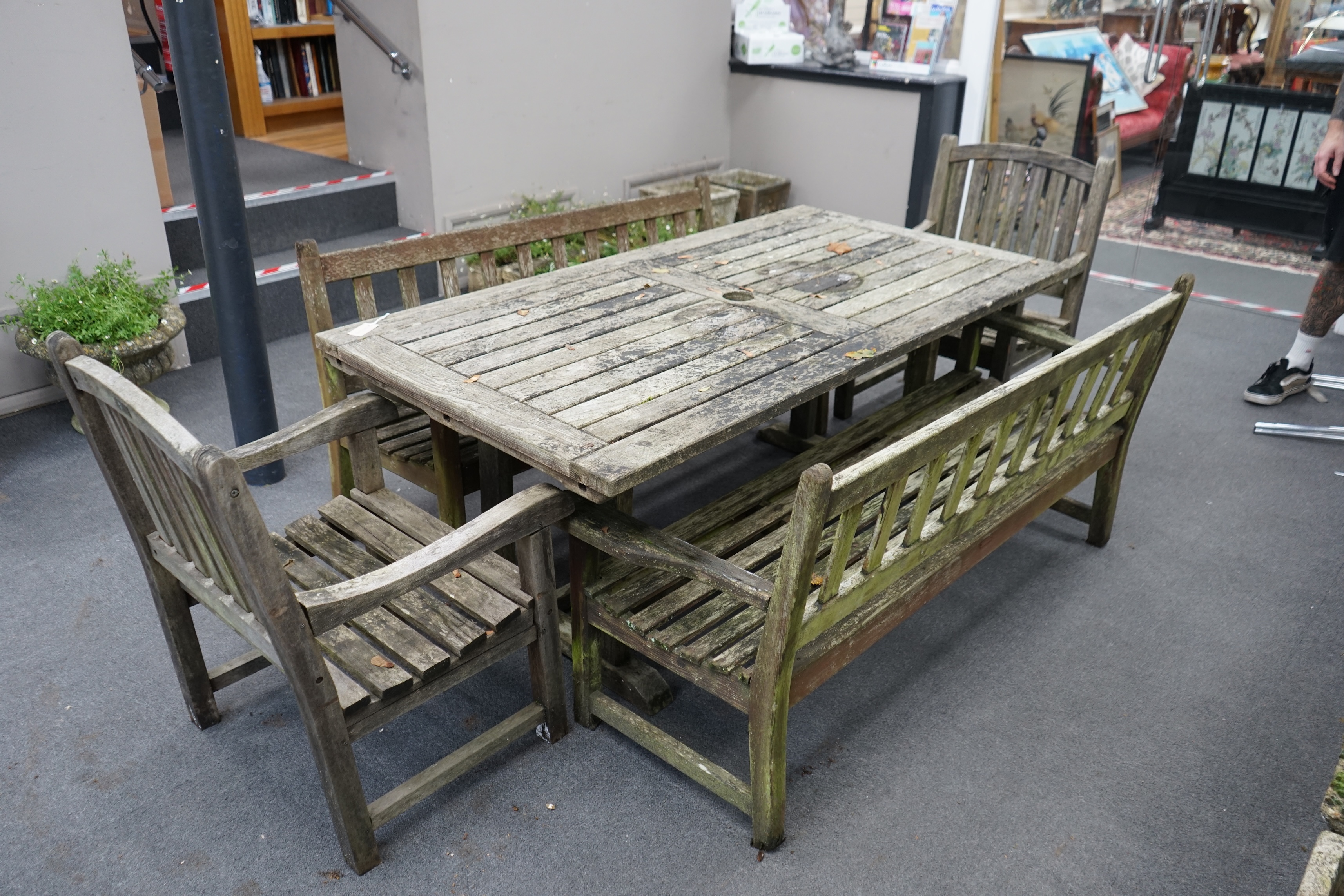 A weathered teak extending garden table, with pair of matching slatted benches and two elbow chairs